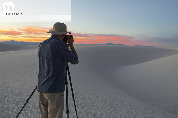 Kaukasischer Mann fotografiert Wüste bei Sonnenuntergang