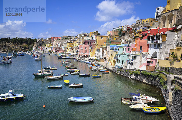Hafen mit vertäuten Booten und farbenfrohen Gebäuden am Hang mit Blick auf die Uferpromenade. Procida  auf den Flegrean Islands vor der Küste von Neapel.