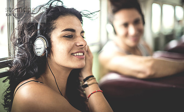 Zwei junge Leute sitzen in einem Bus und tragen Kopfhörer.