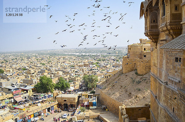 Blick auf die Stadt Jaisalmer vom historischen Hügelkastell mit großen Vögeln in der Luft über dem Markt.