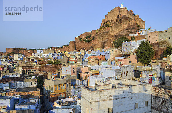 Stadtbild von Jodhpur mit traditionell indigoblau und weiß gestrichenen Häusern und der Mehrangarh-Festung aus dem 15. Jahrhundert auf der Hügelspitze.