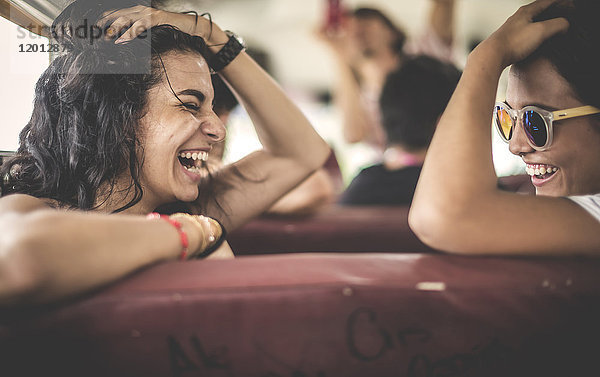 Zwei junge Frauen  Freunde  die zusammen im Schulbus lachen.