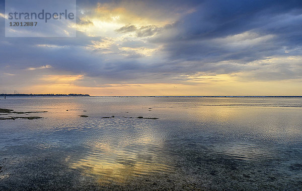 Sonnenuntergang über dem Ozean und Licht- und Wolkenformationen  die sich im seichten Wasser auf der Insel Gili (Indonesien) spiegeln.