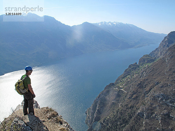 Norditalien  Provinz Trient  Gardasee  ein Mann mit einem Helm steht auf einem Felsen über dem Gardasee