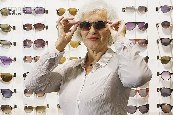Lächelnde Seniorin mit Sonnenbrille im Geschäft