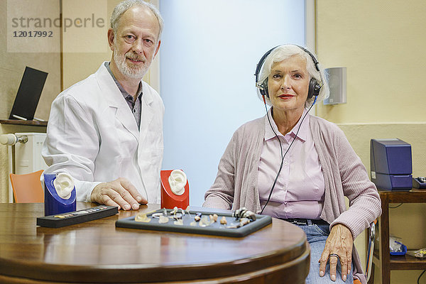 Porträt des Audiologen und Senior-Patienten mit Kopfhörer während der Ohruntersuchung in der Klinik