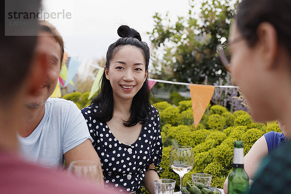 Glückliche junge Frau sitzend mit Freunden auf der Terrasse