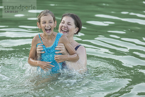 Lächelnde Großmutter genießt mit Enkelin beim Schwimmen im Pool