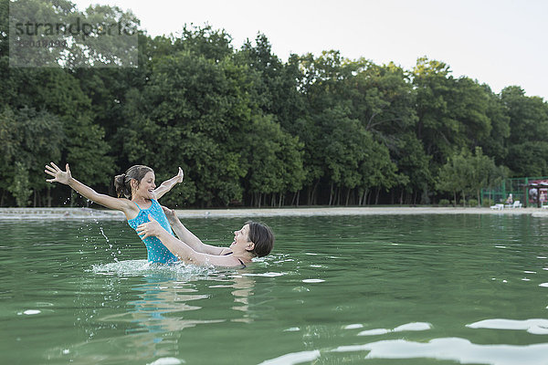 Großmutter genießt mit Enkelin im Swimmingpool gegen Bäume
