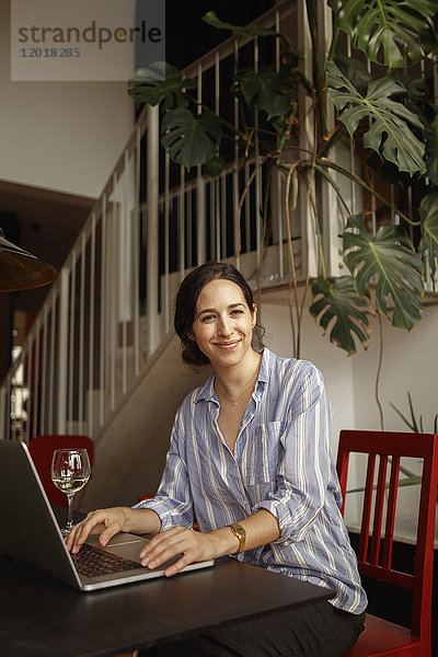 Porträt einer lächelnden jungen Frau mit Laptop zu Hause