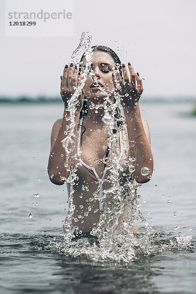 Sinnliche Frau spritzt Wasser im See