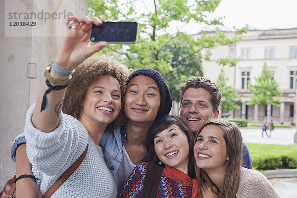 Lächelnde junge Frau nimmt Selfie mit multiethnischen Freunden  Berlin  Deutschland