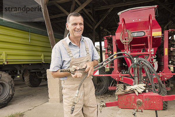Glücklicher reifer Landwirt bei der Arbeit mit Landmaschinen