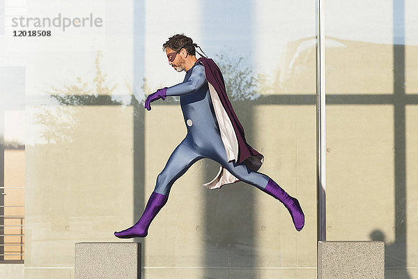 Superheld springt auf Beton gegen Glaswand