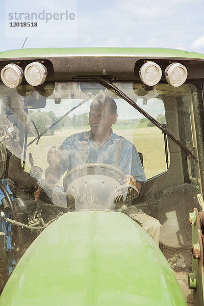 Lächelnder Bauer mit Traktor auf dem Bauernhof an einem sonnigen Tag