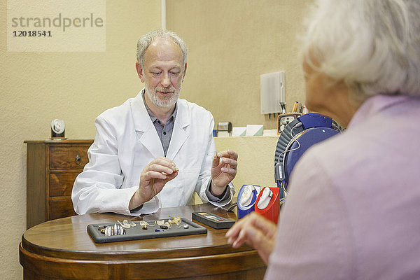 Ärztin mit Hörgeräten erklärt Seniorin in der Klinik