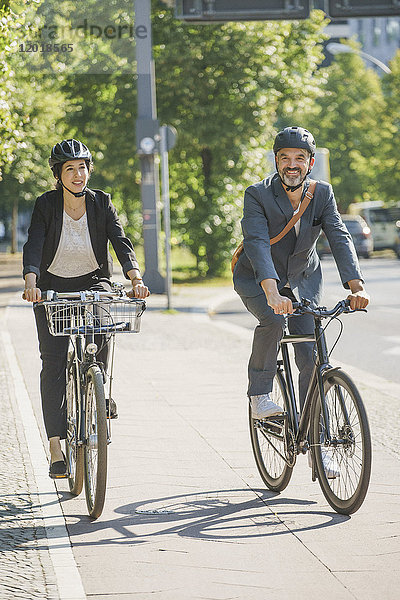 Geschäftskollegen mit dem Fahrrad auf der Straße in der Stadt bei strahlendem Sonnenschein