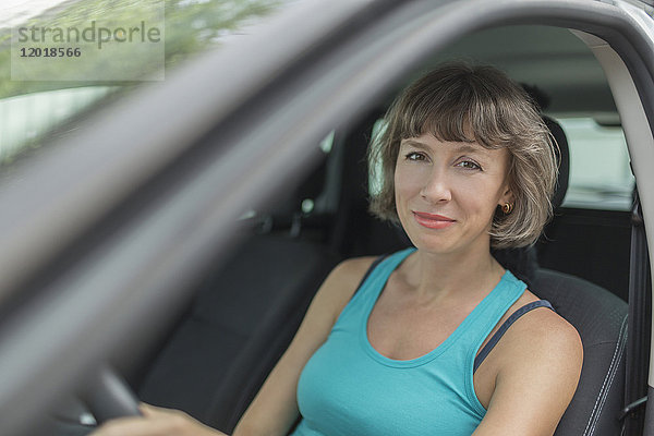 Porträt der lächelnden reifen Frau im Auto sitzend