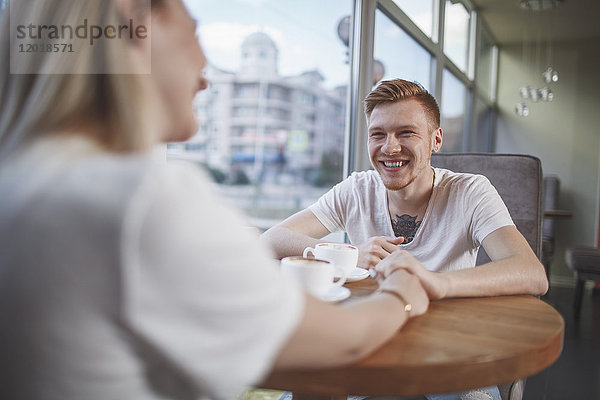 Lächelnder Mann sitzend mit Freundin im Restaurant