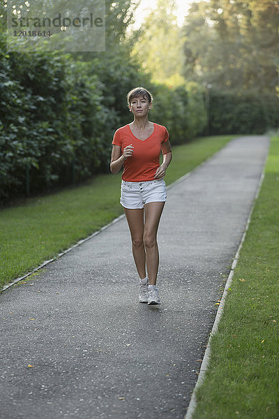 Volle Länge der Frau joggen auf der Straße durch Pflanzen