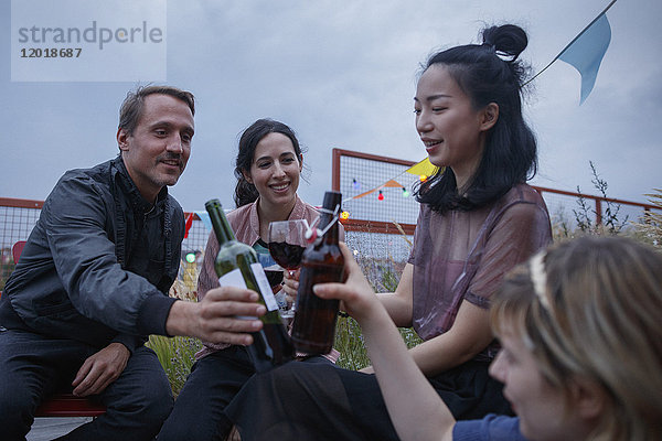 Multi-ethnische Freunde toasten Weinflaschen während der Party auf der Terrasse