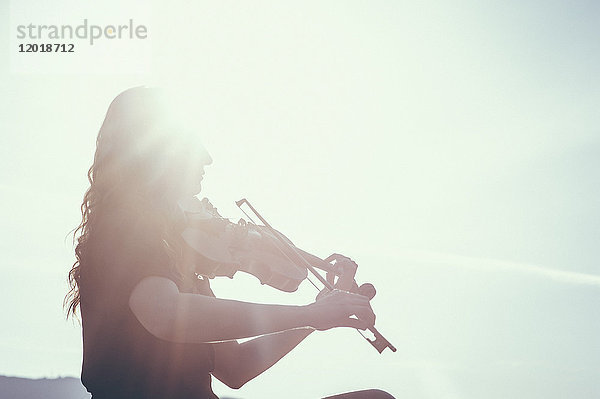 Niederwinkelansicht einer Frau  die an einem sonnigen Tag Geige spielt.