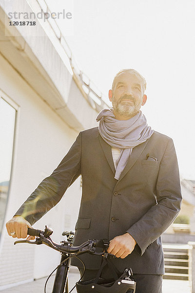 Niederwinkelansicht eines Geschäftsmannes mit Fahrrad in der Stadt an einem sonnigen Tag