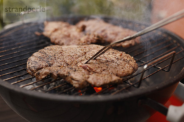 Nahaufnahme des Steaks beim Grillen auf der Terrasse