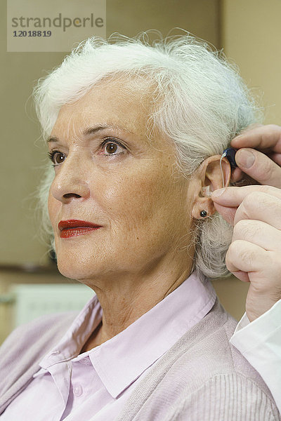 Audiologin unterstützt Seniorin beim Einführen von Hörgeräten in der Klinik