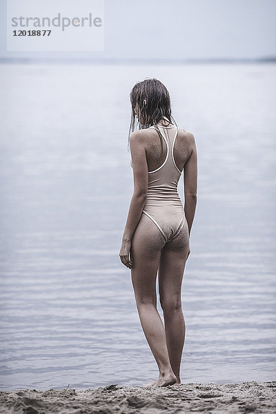 Rückansicht der Frau im einteiligen Badeanzug am Seeufer stehend