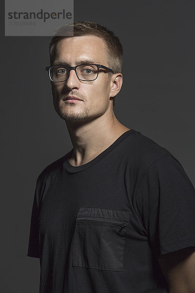 Porträt eines erwachsenen Mannes mit Brille auf grauem Hintergrund