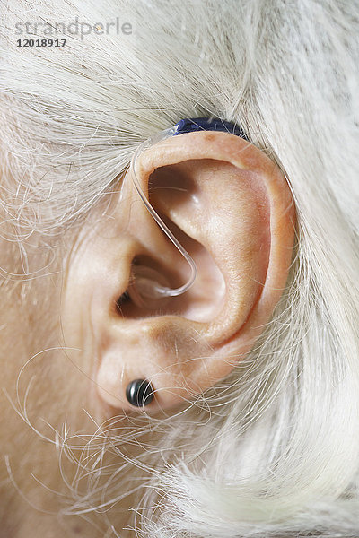Nahaufnahme des Ohres einer älteren Frau mit Hörgerät