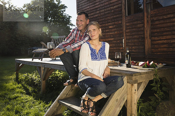 Ein reifes Paar genießt den Wein  während es vor dem Bauernhaus sitzt.