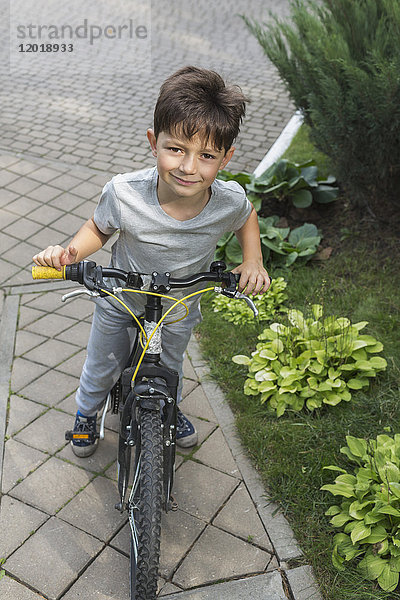Hochwinkel-Porträt eines Jungen auf der Straße von Pflanzen
