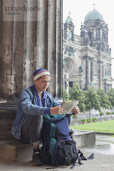 Junger Tourist sitzend mit Karte im Alten Museum gegen den Berliner Dom  Deutschland
