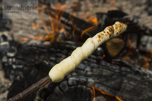 Hochwinkelansicht des Teiges auf Holzspieß über Feuer