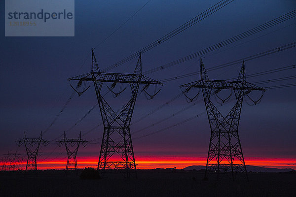 Silhouette Strommasten auf dem Feld gegen den Himmel in der Dämmerung