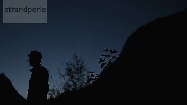 Seitenansicht des auf dem Berg stehenden Silhouettenmannes gegen den klaren Himmel