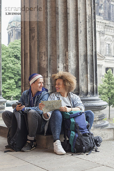 Lächelnder junger Tourist sitzend mit Karte im Alten Museum  Berlin  Deutschland
