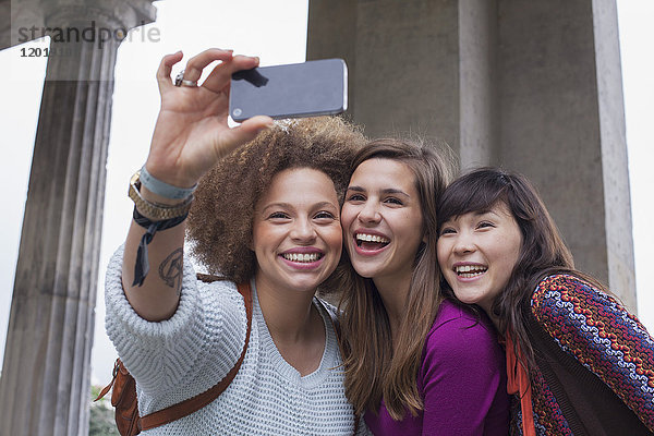 Niedriger Blickwinkel auf lächelnde junge Freundinnen  die Selfie nehmen.