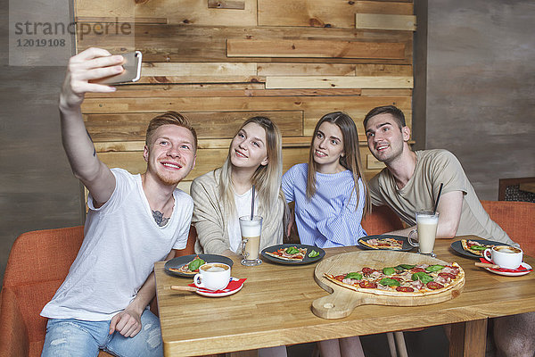 Junge Freunde  die im Restaurant sitzen und Selfie nehmen