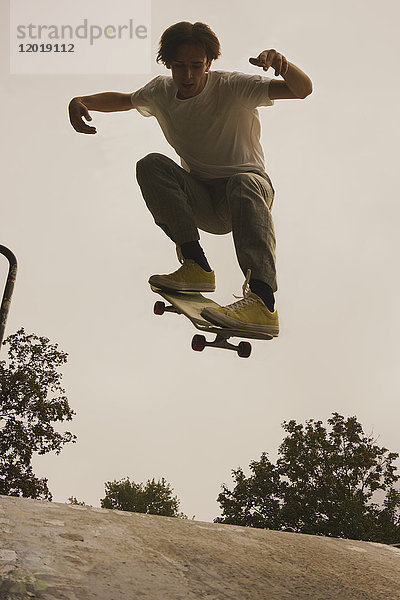 Volle Länge des jungen Mannes Skateboarden im Park gegen den klaren Himmel