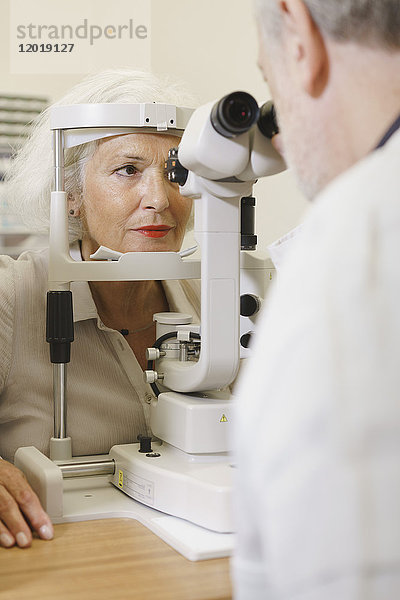 Arzt untersucht das Auge einer älteren Frau in der Klinik