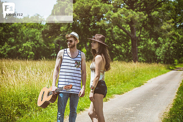 Porträt eines jungen Paares Hipsterfahrt auf dem Lande  eine Gitarre in der Hand