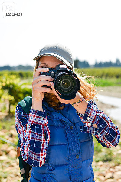 Fröhliche junge Frau beim Wandern und Fotografieren mit ihrer Spiegelreflexkamera - Cepage Grenache  Chateauneuf du Pape  cotes du Rhone  Frankreich