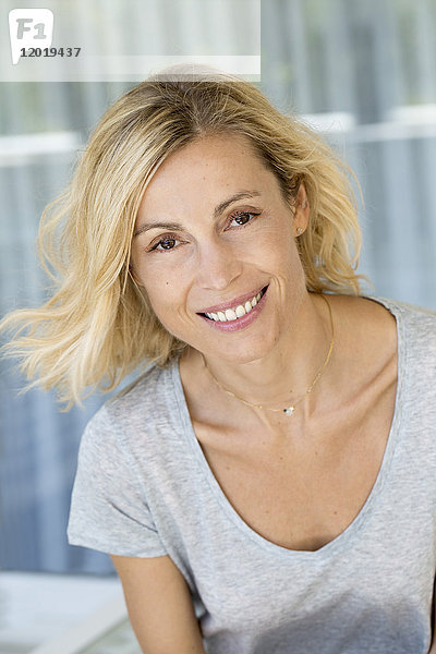 Porträt einer schönen lächelnden blonden Frau mit grauem T-Shirt.