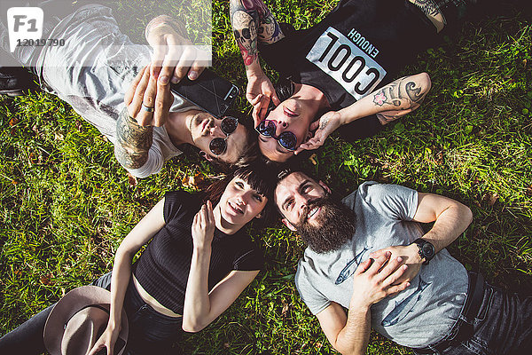 Selfie einer Gruppe von jungen Hipstern im Gras liegend