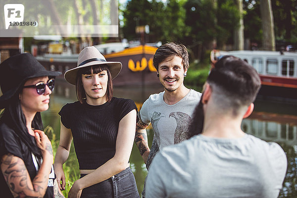 Hipster-Jugendgruppe im Gespräch am Ufer der Garonne  im Hintergrund Lastkähne