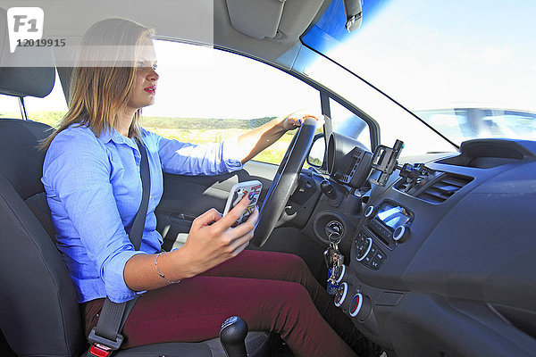 Frankreich  Frau benutzt Smartphone in ihrem Auto.