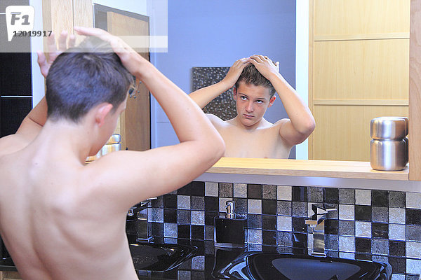 Frankreich  ein Junge im Badezimmer  der seine Haare im Spiegel betrachtet.